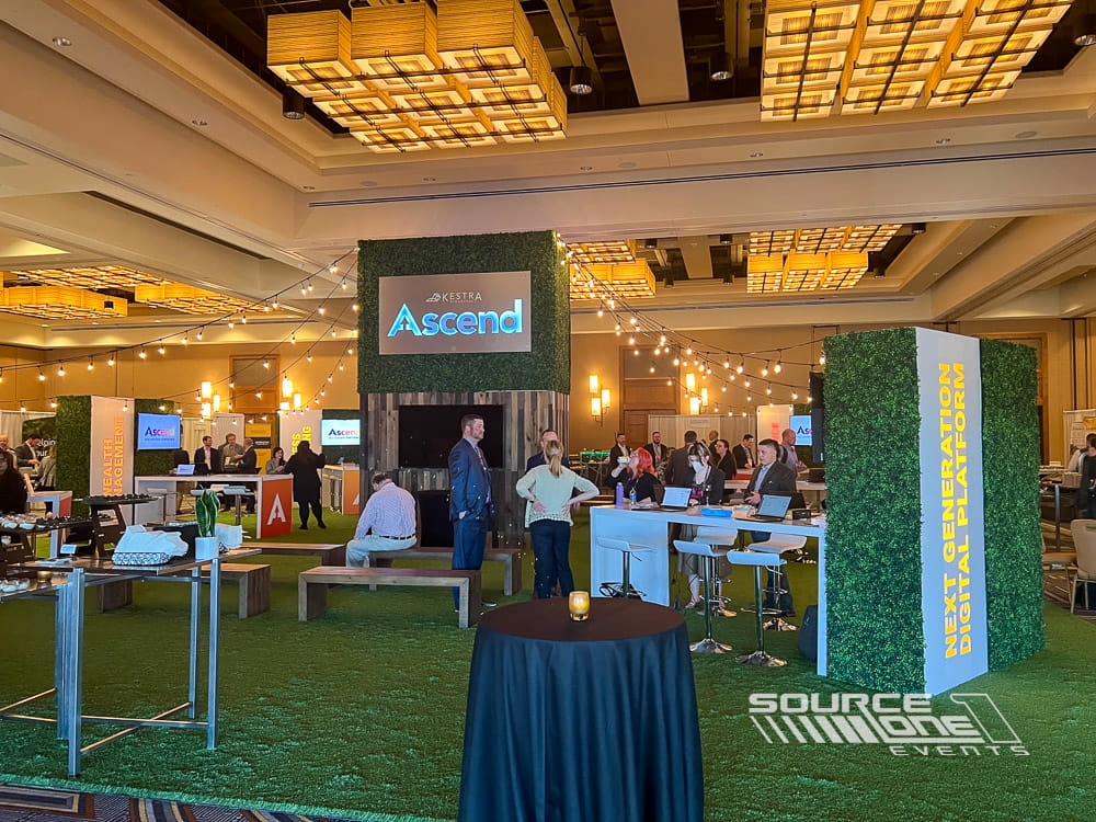 Spacious networking hub featuring branded overhead structures, seating areas, and premium environmental graphics.