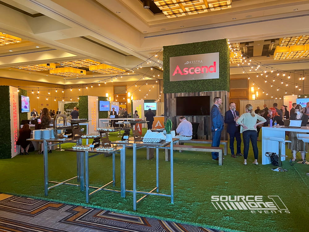 Open networking hub featuring green environmental graphics, lounge seating, and collaborative attendee gathering space.