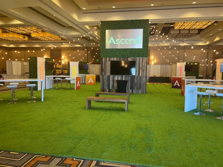 Indoor networking area with artificial turf and event signage.