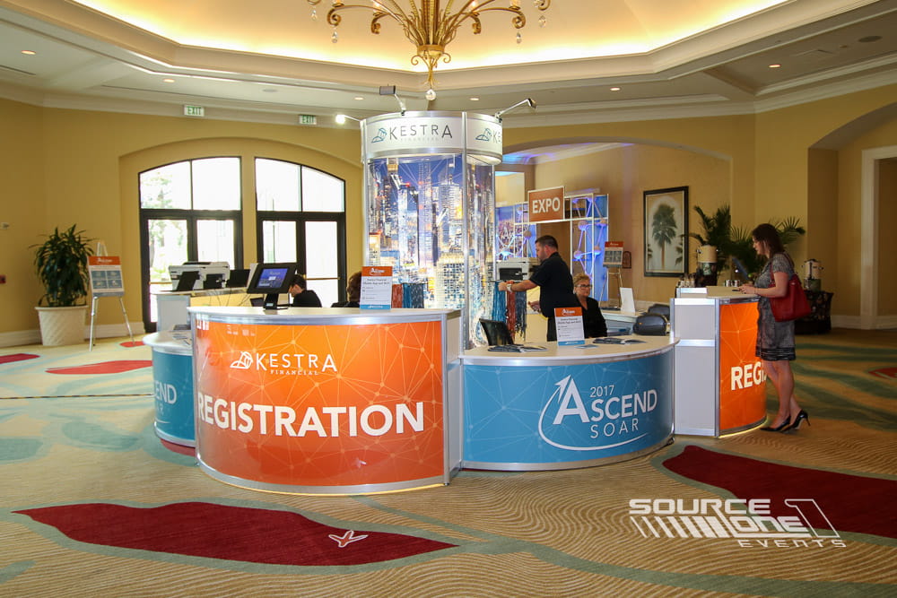 Contemporary registration counter with custom blue branding, illuminated displays, and attendee check-in services.