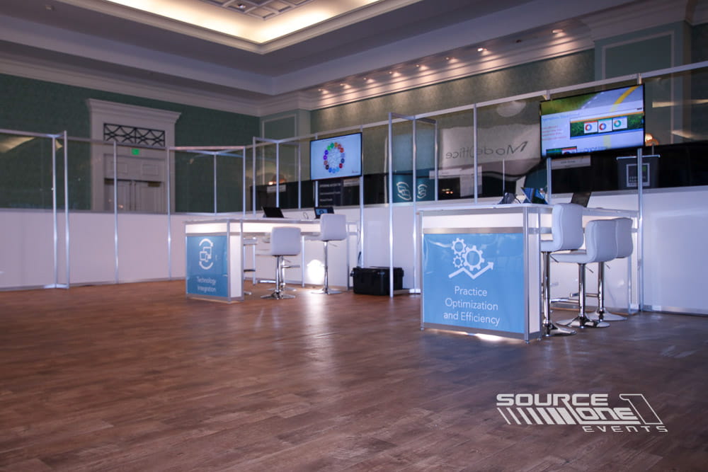 Branded reception and workstation with digital displays supporting attendee engagement during an event.