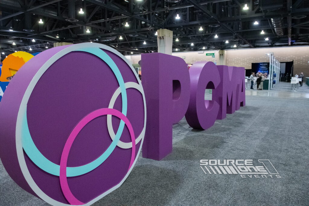 Oversized dimensional purple event letters creating a dramatic branded photo opportunity within a convention environment.