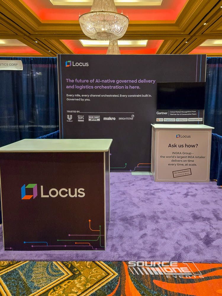 Custom healthcare exhibit featuring dark branded graphics, integrated digital monitor, reception counter, and modern architectural finishes.