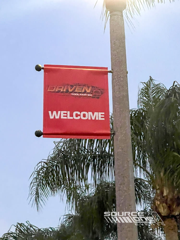 Outdoor feather flag welcoming conference attendees with branded event graphics positioned near the venue entrance.