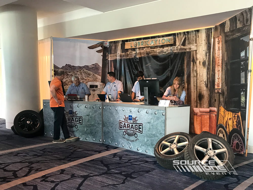 Large registration counter featuring wood finishes, overhead signage, and multiple attendee check-in stations.