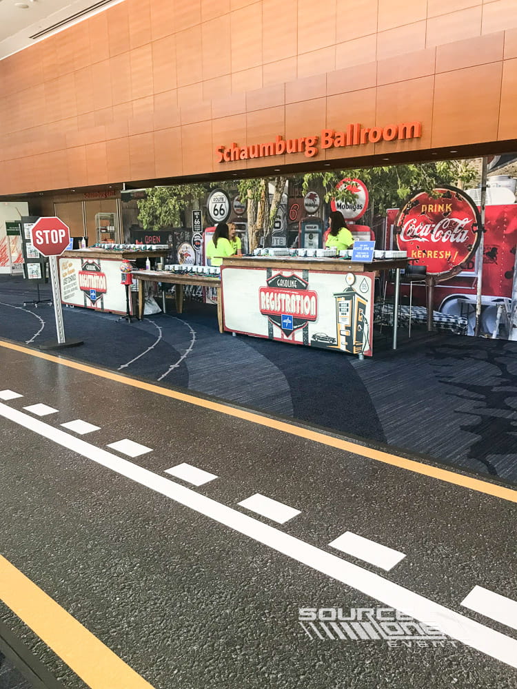 Registration and information desk with bold branded graphics, attendee assistance counters, and modern convention center design.