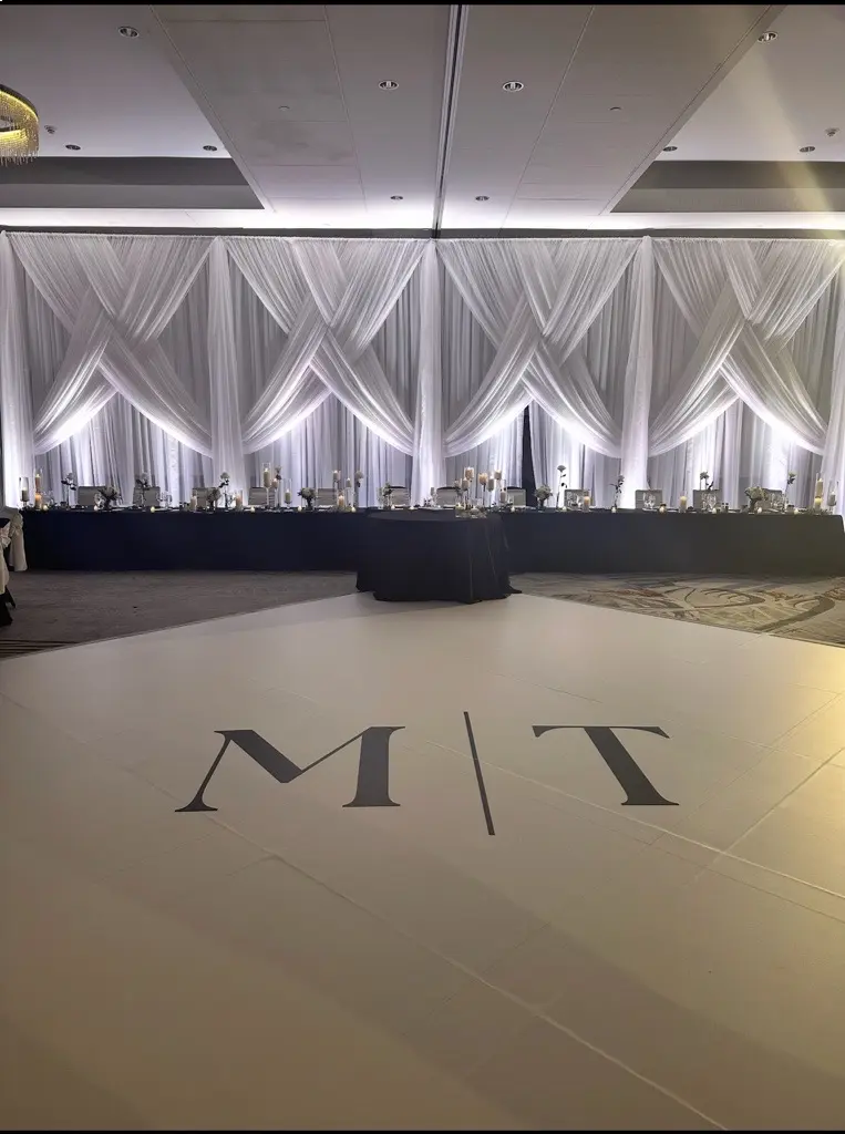 Ballroom or event venue with decorative white drapery and lighting.