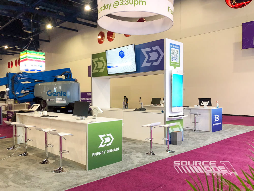 Open-concept custom exhibit with illuminated graphics, reception counter, and modern exhibit fabrication designed for attendee engagement.
