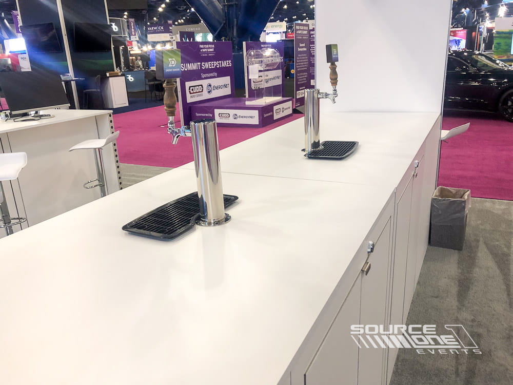 Contemporary exhibit featuring interactive touchscreen kiosks, branded counters, and product presentation displays.