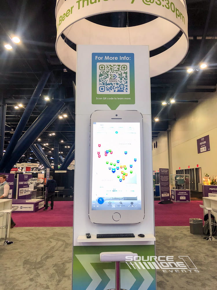 Freestanding digital monitor kiosk featuring custom branded graphics and interactive attendee information at a trade show exhibit.