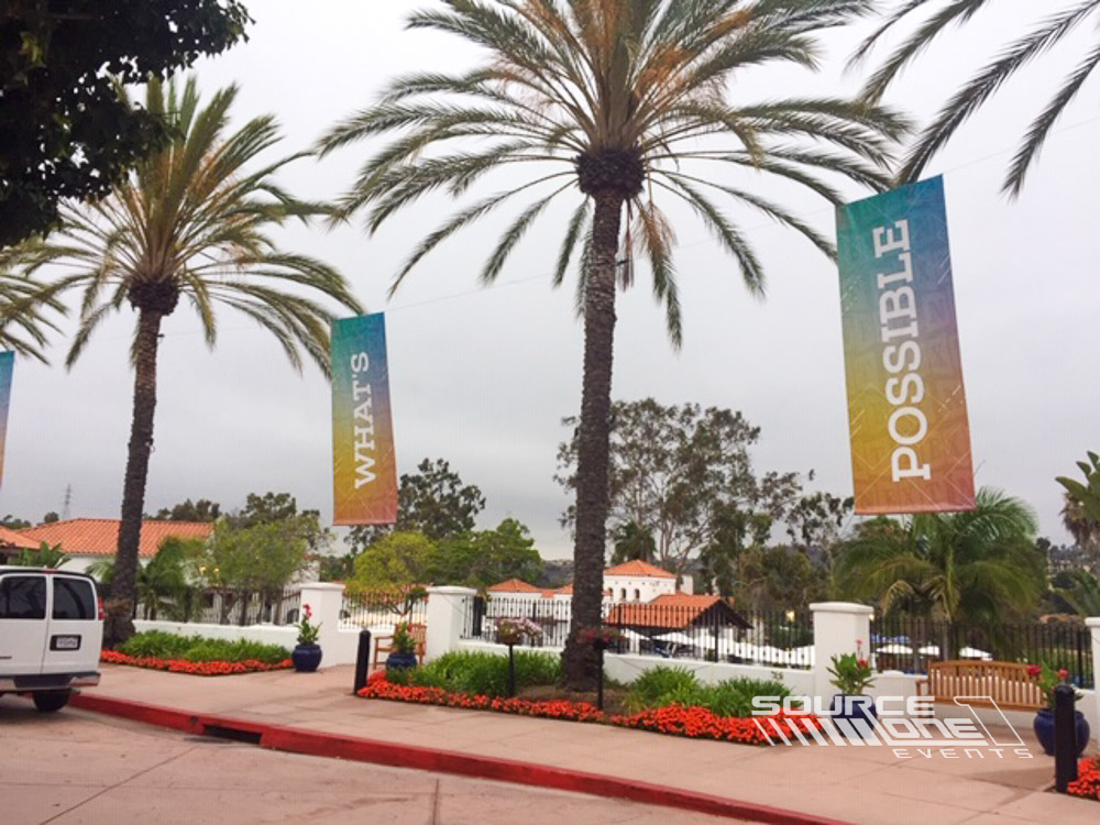 Outdoor building-mounted banner promoting the conference entrance with large colorful event graphics.
