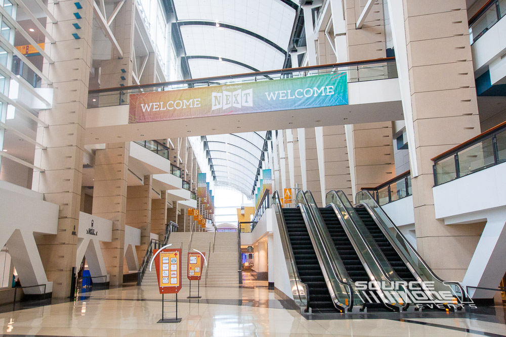 Tall vertical hanging banner suspended from the convention ceiling displaying colorful conference graphics.