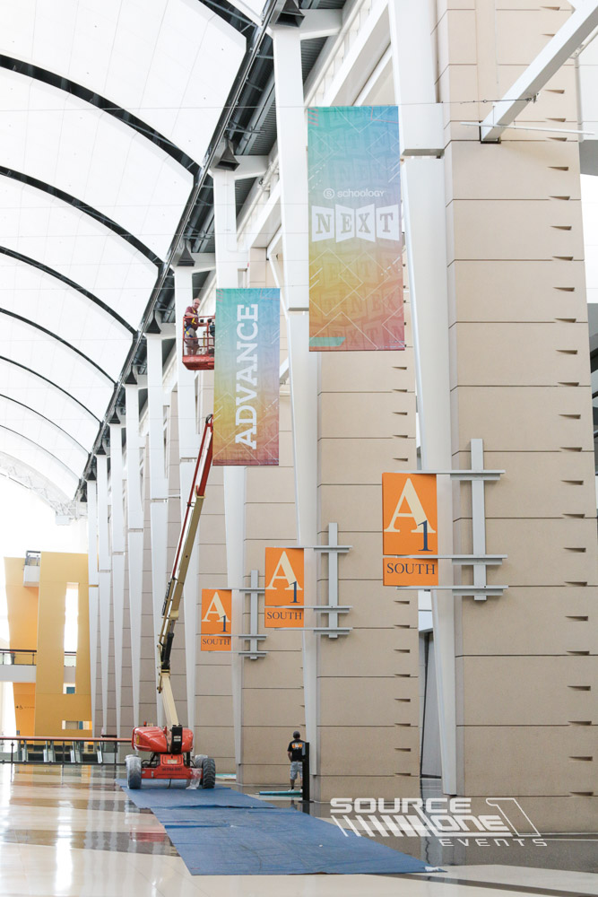 Outdoor pole banners welcoming attendees to NEXT conference with colorful branding displayed throughout the resort entrance.