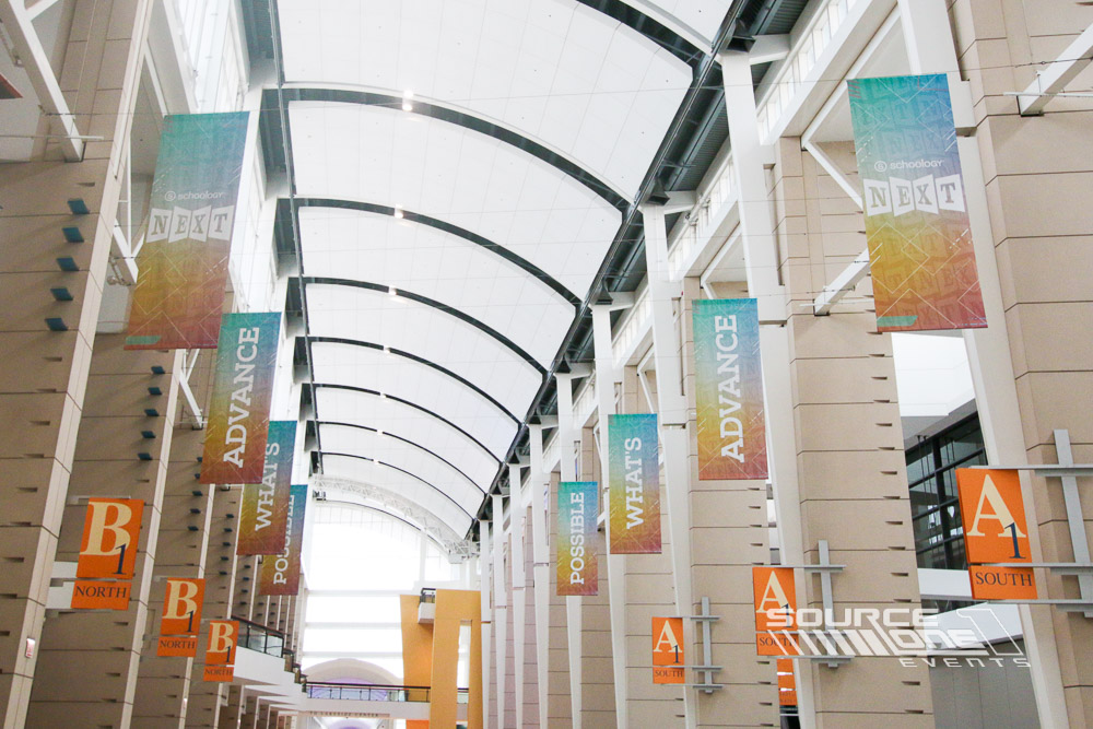 Palm tree entrance banners featuring vibrant conference branding leading attendees toward registration.
