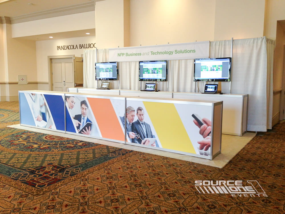 Registration welcome desk with branded graphics, digital displays, and professional attendee check-in counters for a corporate conference.