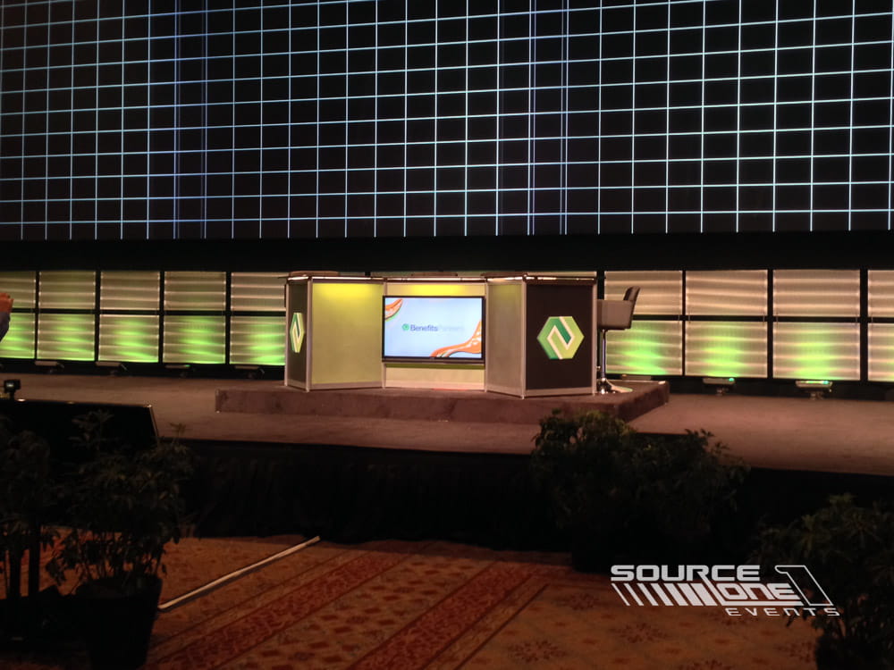 Registration or presentation counter with branded NFP graphics, blue accent lighting, and modern event design.