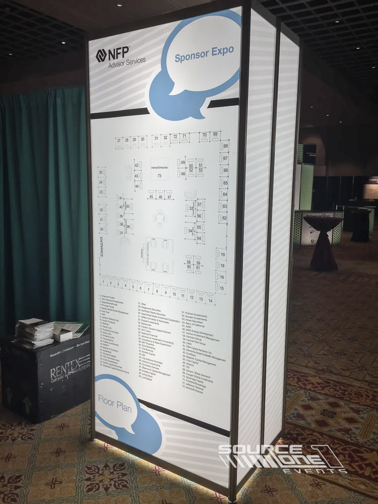 Double-sided white backlit tower display with clean corporate branding positioned within a conference registration area.