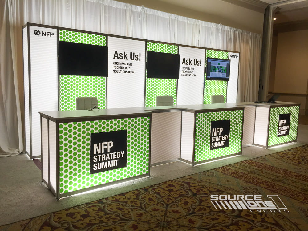 Green and white custom registration counter with branded check-in stations, information desk, and attendee assistance area.