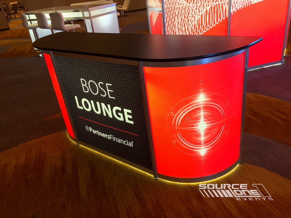 Curved backlit reception counter with custom branding for conference attendees.
