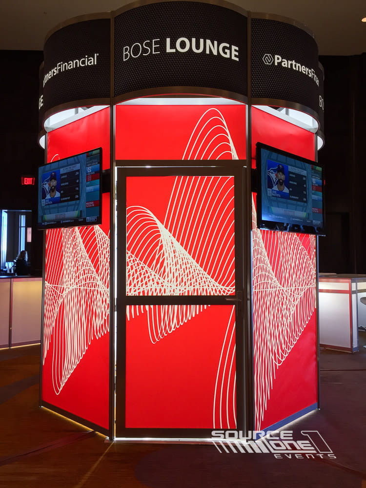Red cylindrical backlit tower with integrated LED displays serving as a high-impact branding element for conference registration.