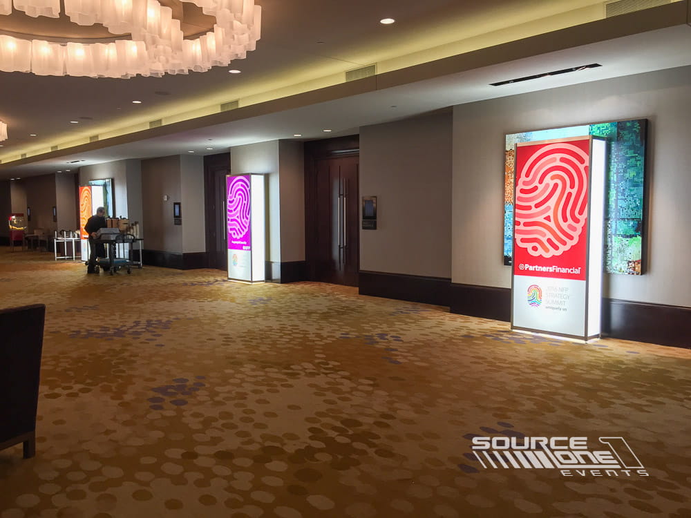 Elegant registration entrance with illuminated purple backlit towers and branded conference graphics enhancing attendee wayfinding.