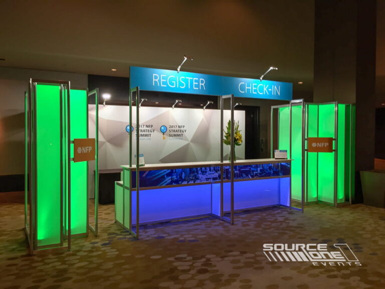 Bright green illuminated registration counter with clean architectural design and branded conference graphics.