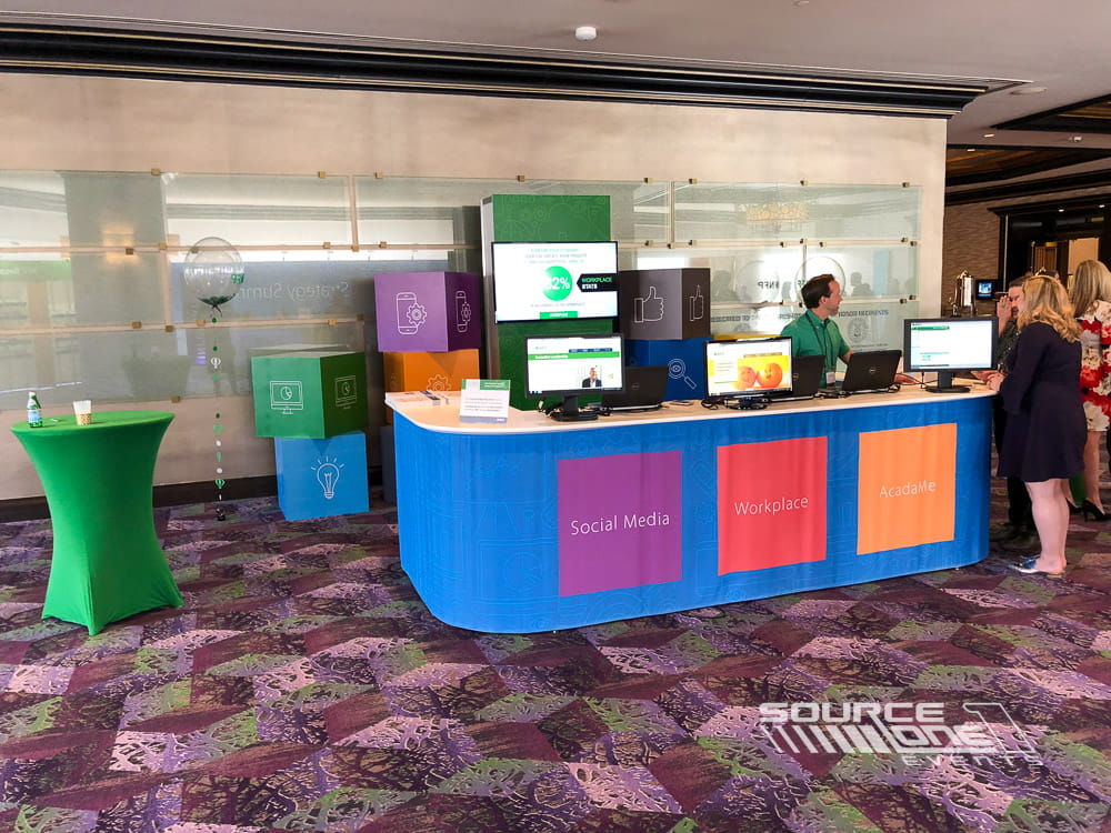 Custom-built registration counter featuring vibrant blue and orange branding with integrated attendee service desks.