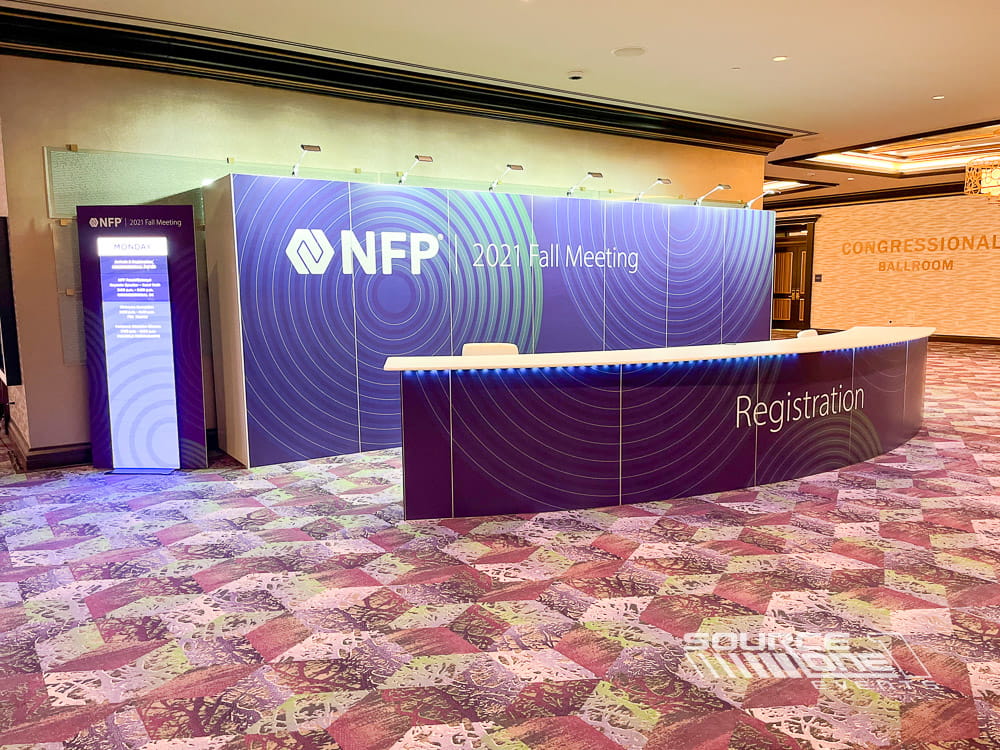 Purple branded registration counter with integrated sponsor graphics and efficient attendee service layout.