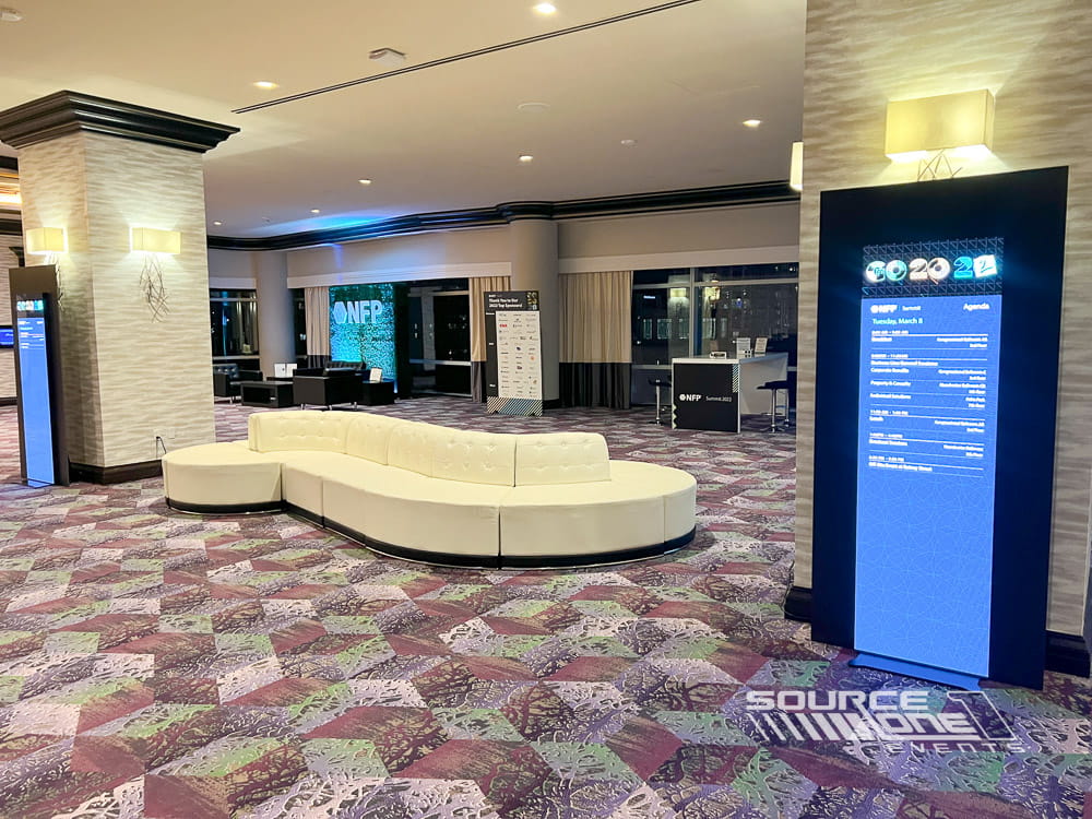 Elegant conference lounge with digital LED poster displays, soft lighting, and premium attendee networking environment.