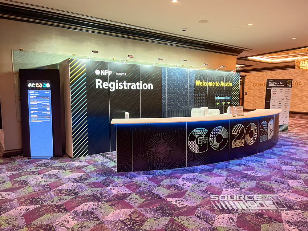 Modern registration counter with blue illuminated graphics and branded attendee check-in stations.