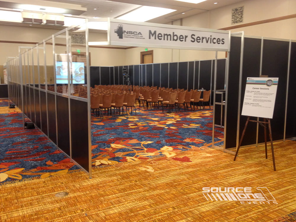 Branded member services presentation room with theater seating, conference stage, and informational displays for attendees.