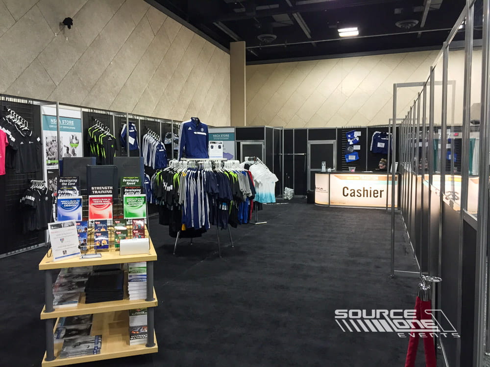 Interior view of a conference merchandise store displaying apparel, accessories, and organized retail fixtures.