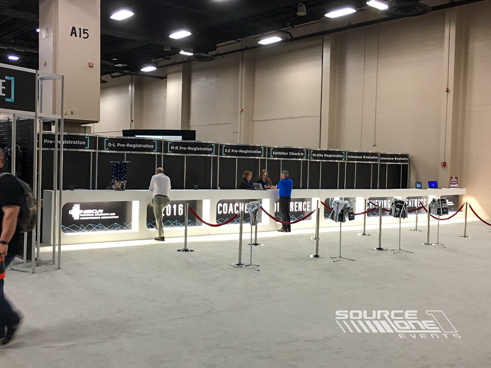 Open registration area with long attendee service counters, neutral finishes, and professional conference branding.