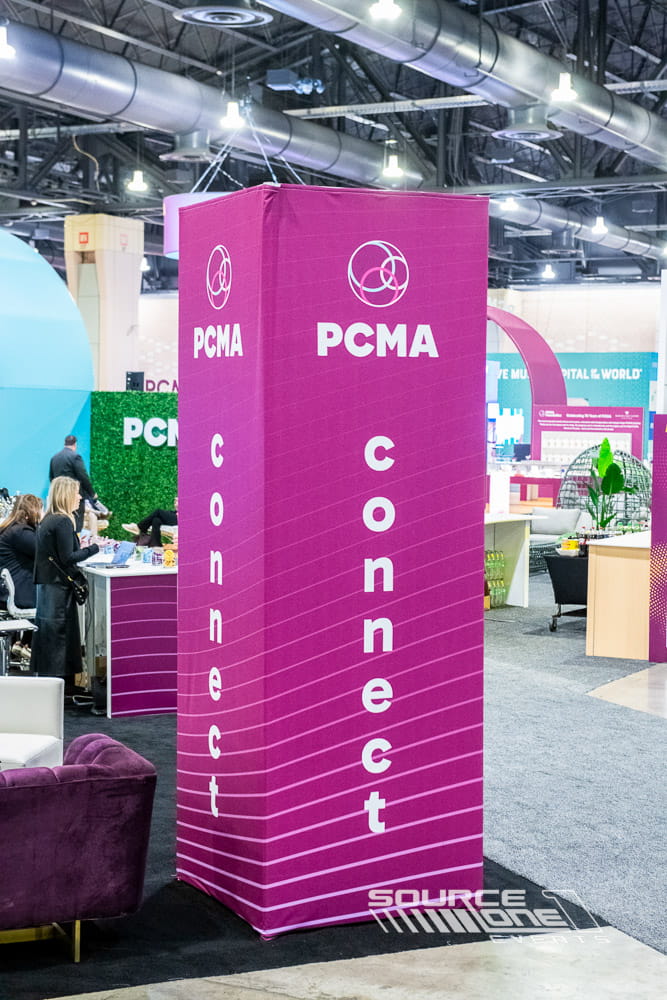 Bright magenta cylindrical branded tower marking the Connect Café networking area at PCMA Convening Leaders, designed for attendee wayfinding and engagement.