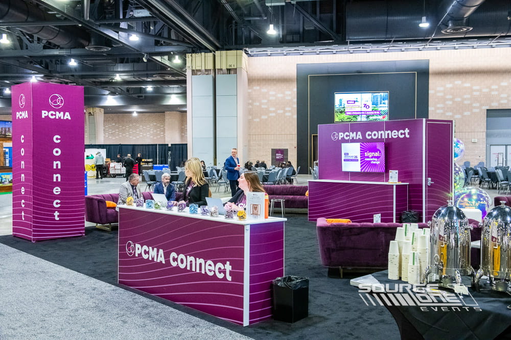 Open networking café featuring branded environmental graphics, lounge seating, collaboration tables, and attendee gathering spaces at PCMA Convening Leaders.