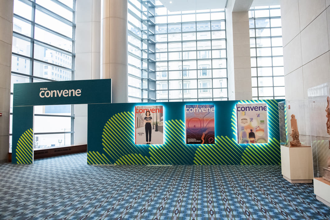 Custom PCMA Convene magazine display featuring illuminated publication covers and branded environmental graphics inside a convention center.