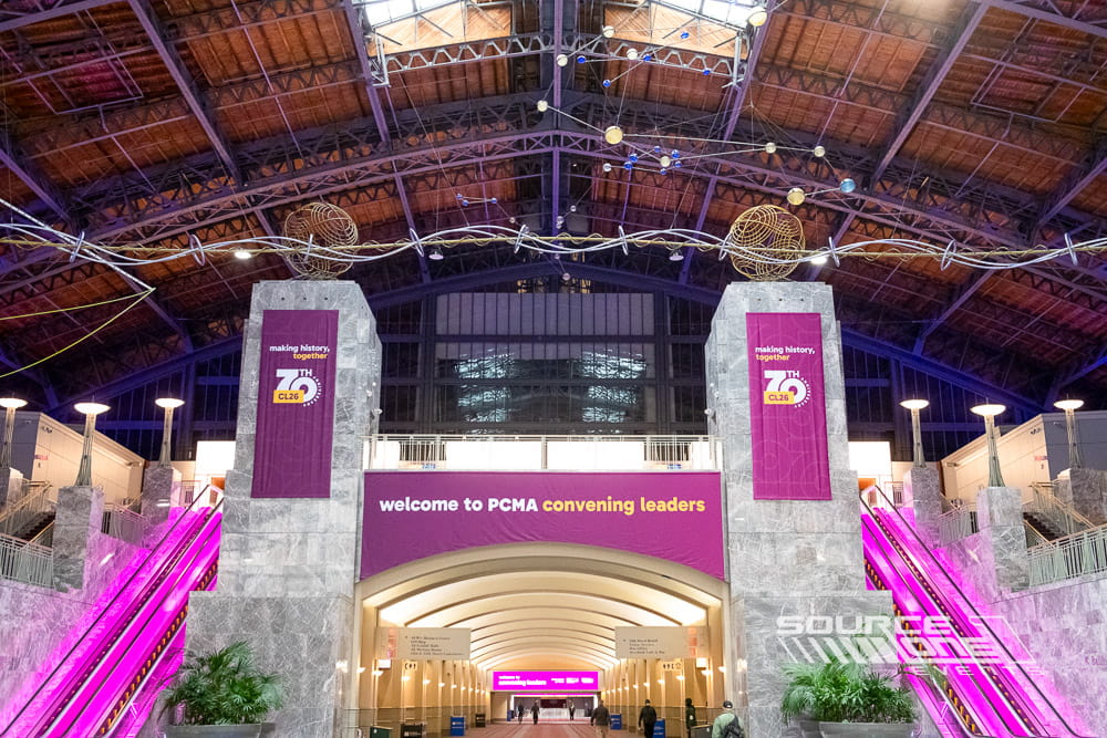 Hanging fabric banners with custom branding installed over exhibit aisles to improve attendee wayfinding.