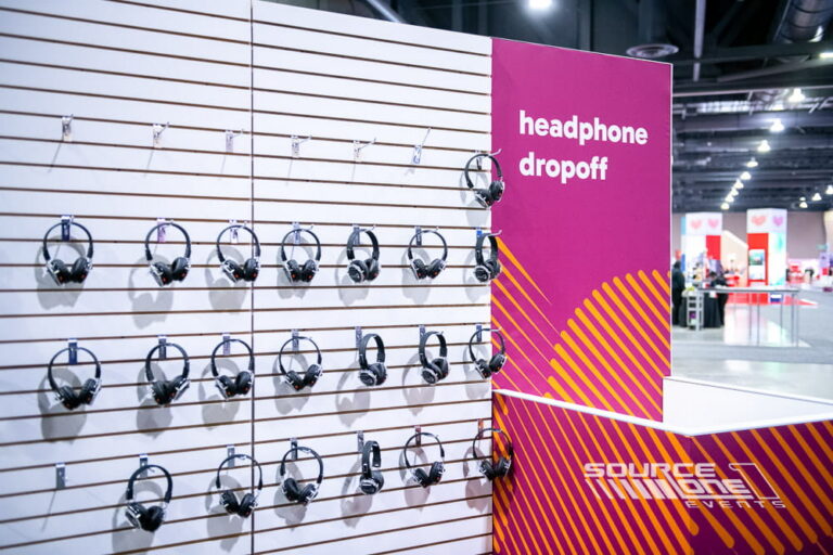 Branded headphone drop-off wall with organized listening stations supporting interactive attendee engagement.