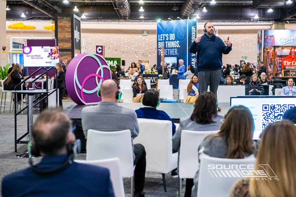 Conference presentation stage featuring custom branding and audience seating.