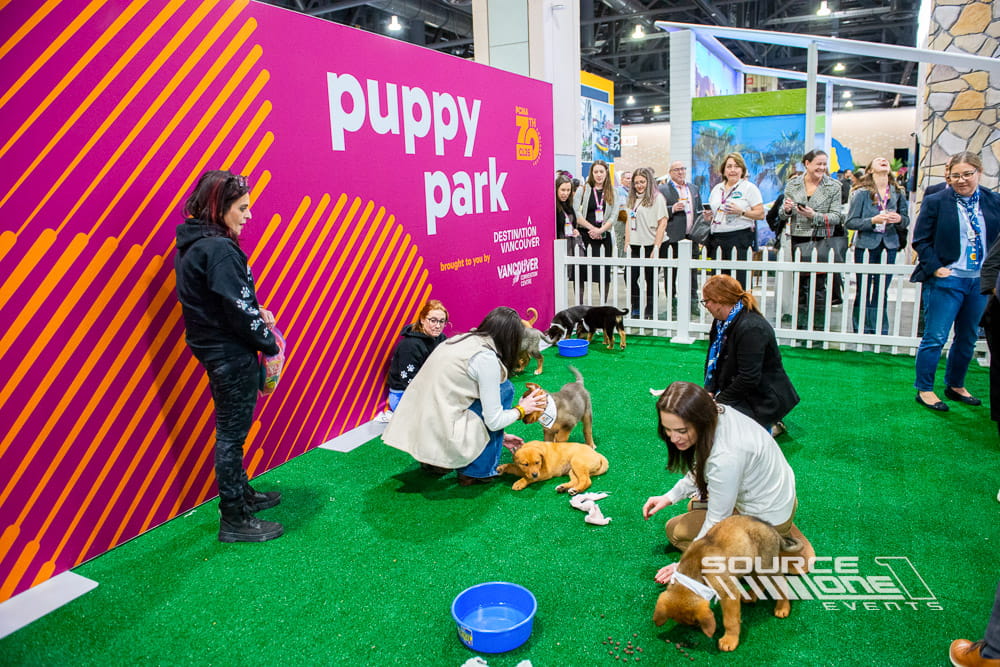 Interactive Puppy Park activation at PCMA Convening Leaders featuring bright pink environmental graphics, branded seating, and a relaxing attendee engagement space designed for networking and wellness.