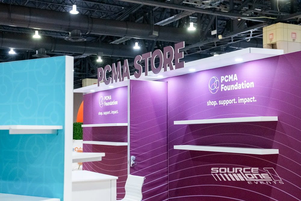 Large illuminated 3D letters identifying the PCMA Store inside the convention center.