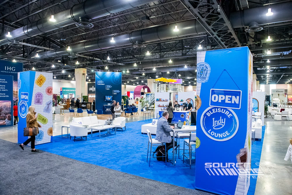 Visit Indy destination marketing exhibit featuring vibrant blue branding, digital displays, and interactive visitor engagement spaces.