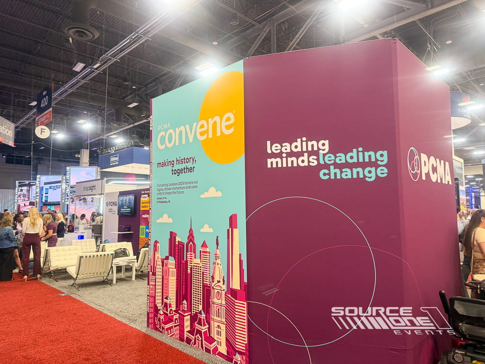 Large custom exhibit with colorful architectural branding, illuminated graphics, and collaborative meeting areas for international trade show attendees.