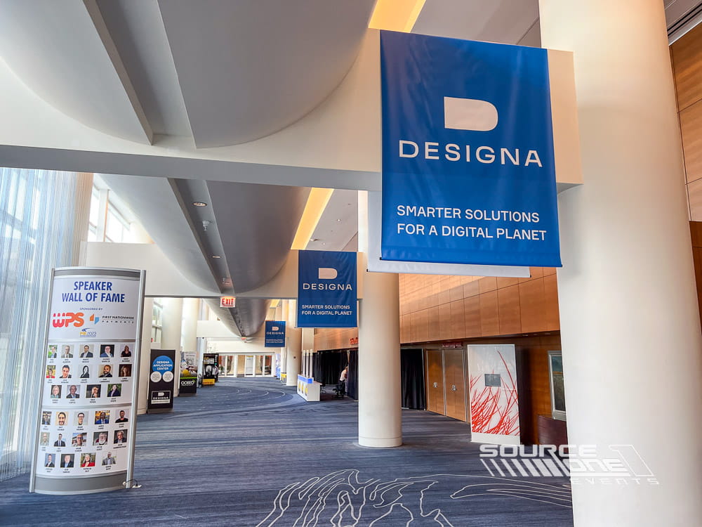 Outdoor feather flags installed along a conference entrance roadway to welcome attendees and reinforce event branding.