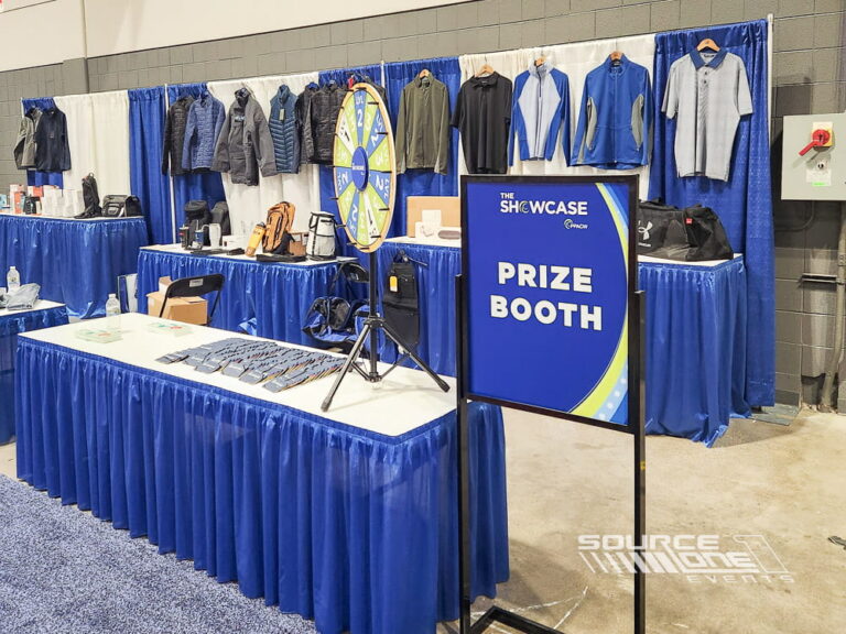 Blue freestanding prize booth easel sign displayed inside a trade show exhibit, providing attendee information and branded event messaging.