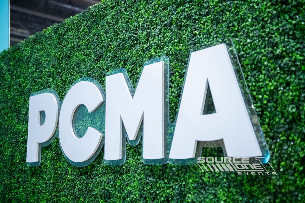 Large white dimensional PVC letters mounted against a green living wall, creating bold custom event branding.