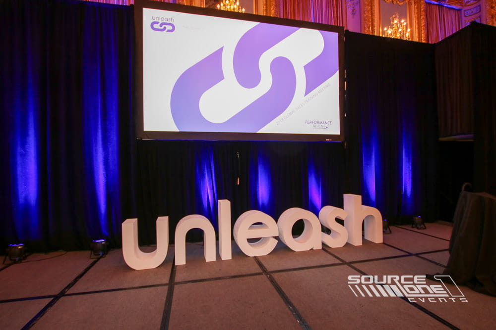 Large illuminated 3D logo displayed on the conference presentation stage.