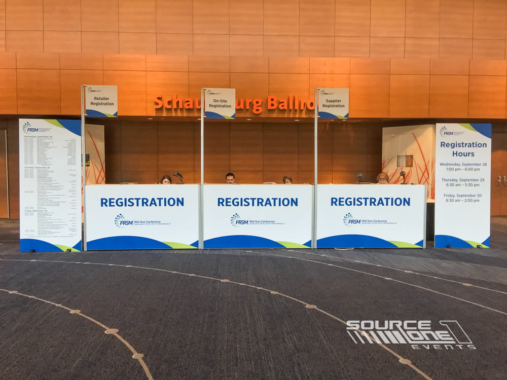 Long registration counter with multiple check-in stations and clean branded graphics providing efficient attendee registration.