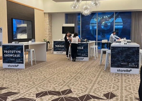 Branded trade show hospitality area with modern lounge furnishings and displays