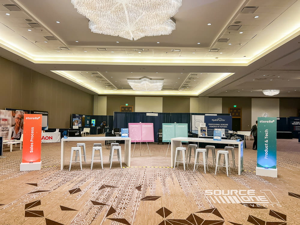 Open networking area with café tables, modern seating, and collaborative meeting space designed for conference attendees.